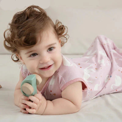 bambine souriante en gigoteuse rose avec un jouet 