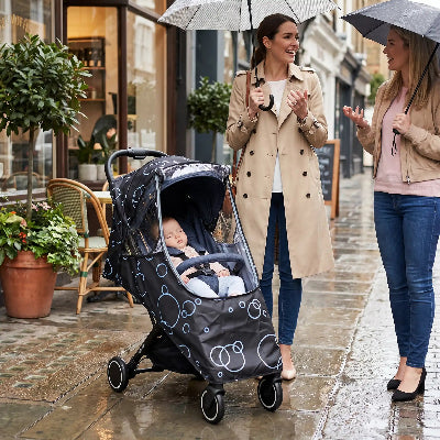 Housse de pluie universelle pour poussette : bébé faisant dodo pendant que maman parle avec son amie
