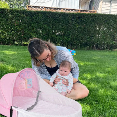 Lit de voyage pour bébé rose installé au parc, antimoustiques