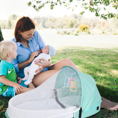 Lit de voyage pour bébé vert menthe installé au parc, prêt à l'emploi