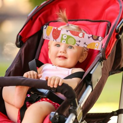 Support de tête réglable Hiboux rose | RelaxBébé™ – Petite fille souriante dans sa poussette