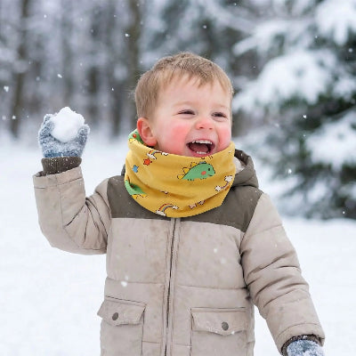 Tour de cou bebe Dinosaure jaune garçon souriant tirant une motte de neige 