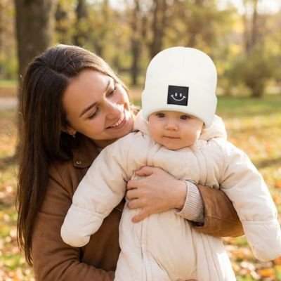 Bonnet bebe blanc dans les bras de maman