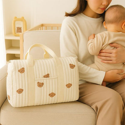 Sac à langer bébé beige ourson sur le sofa avec bébé et maman
